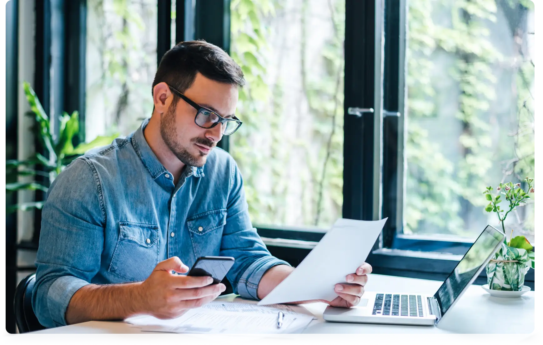 Man working on laptop and phone.